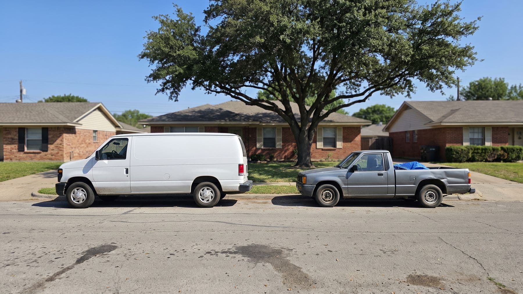 Illustration: a white high-roof cargo van and a smaller gray pickup parked nose to tail on a street of brick ranch houses in Arlington, Texas.