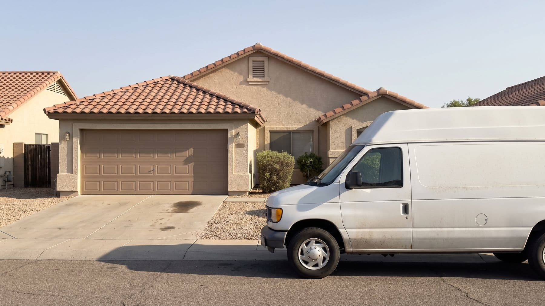 Illustration: a white high-roof cargo van at the curb of a beige stucco ranch in Mesa, Arizona, the driveway beside it empty.