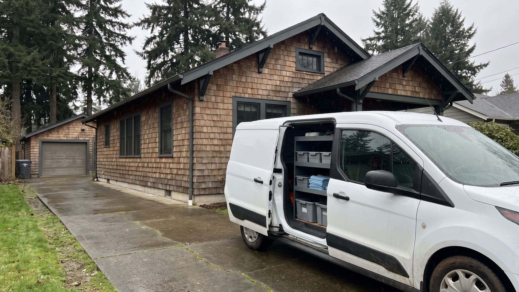Illustration: a white cargo van with its sliding door open up the driveway of a cedar-shingle bungalow in Portland, Oregon, light rain.